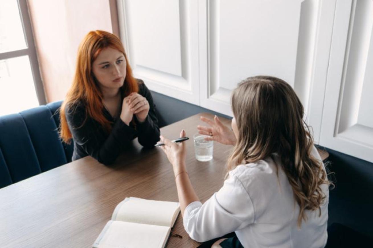 Photo showing two women talking together at a table Photo showing two women talking together at a table
