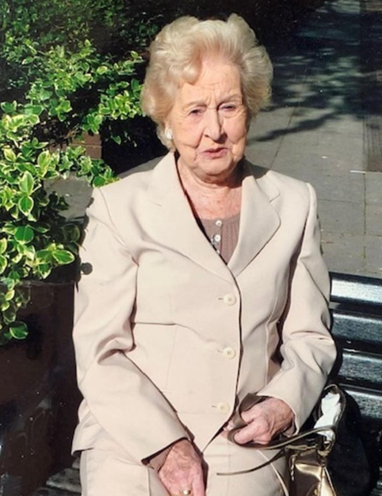 Tessa well dressed in a cream suit looking at the camera 
